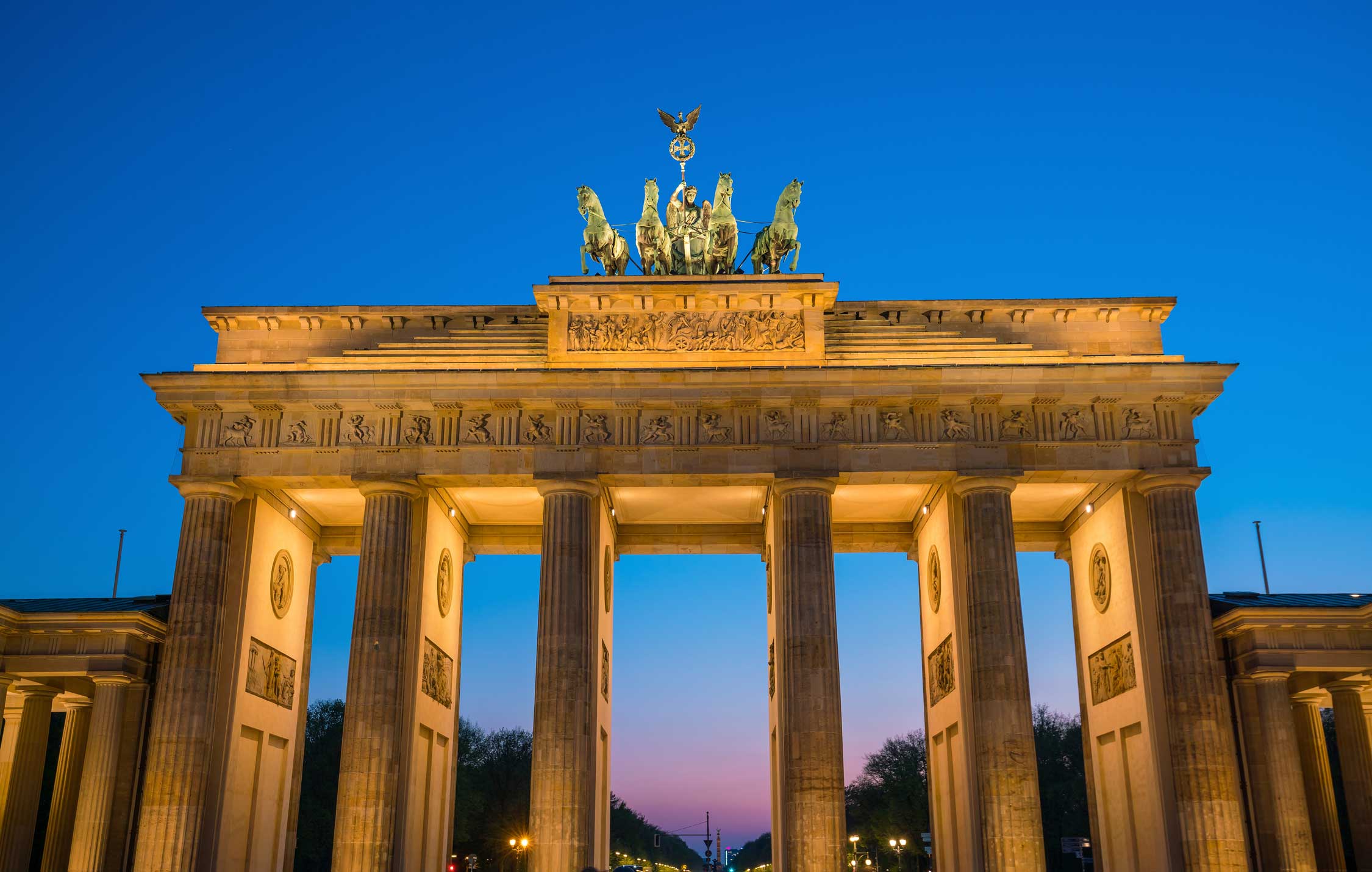 La Porta di Brandeburgo illuminata di notte a Berlino, simbolo storico della riunificazione tedesca e monumento neoclassico.