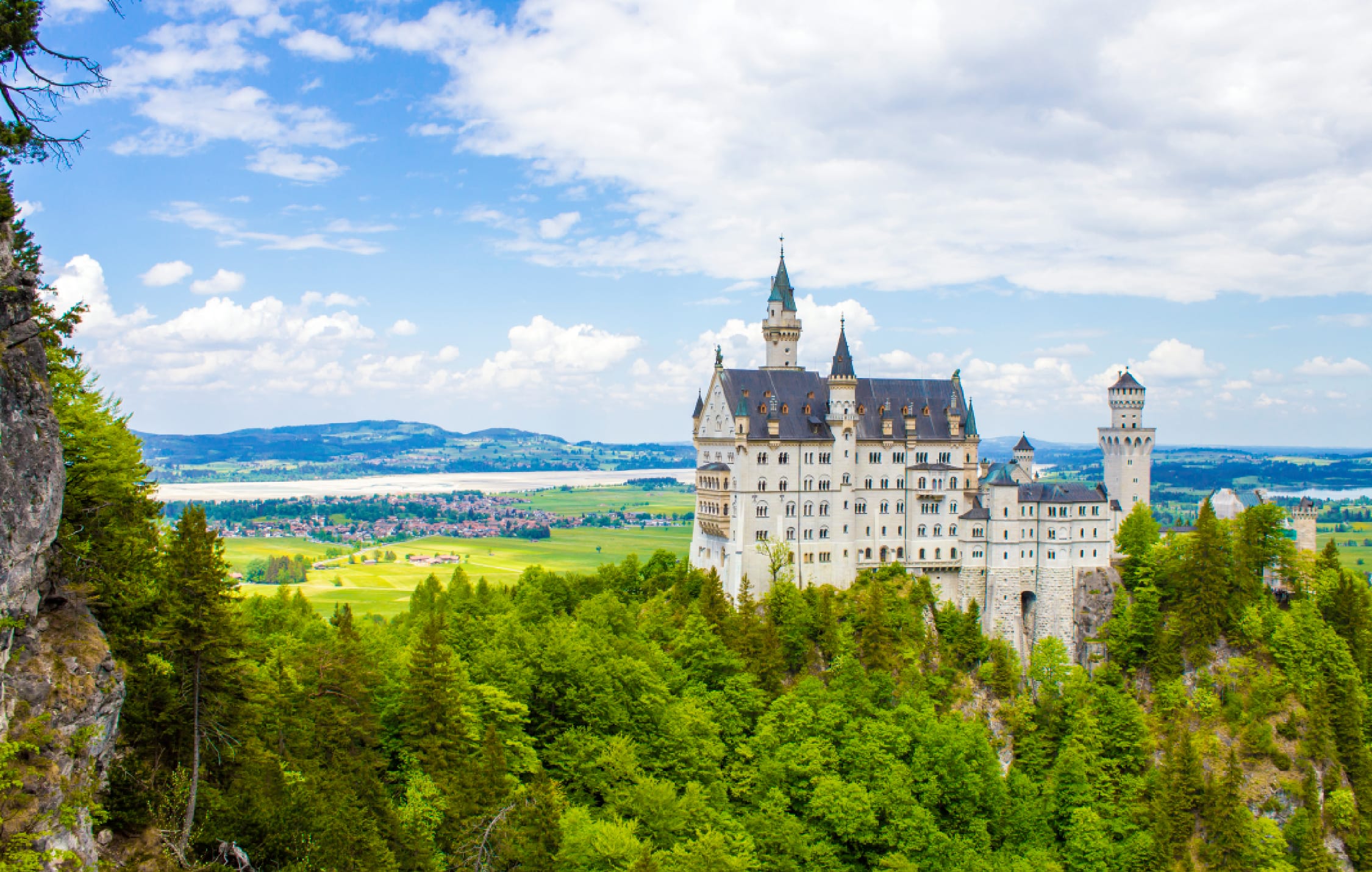 Vista laterale delle torri bianche del castello di Neuschwanstein con lo sfondo delle montagne e della gola di Pöllat.